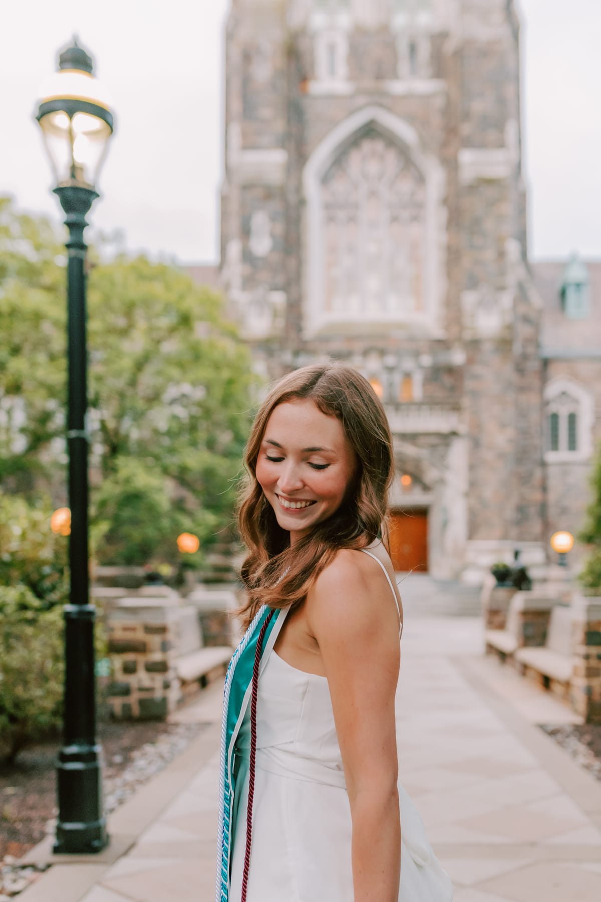 Sarah smiling in front of a Lehigh University chapel at graduation