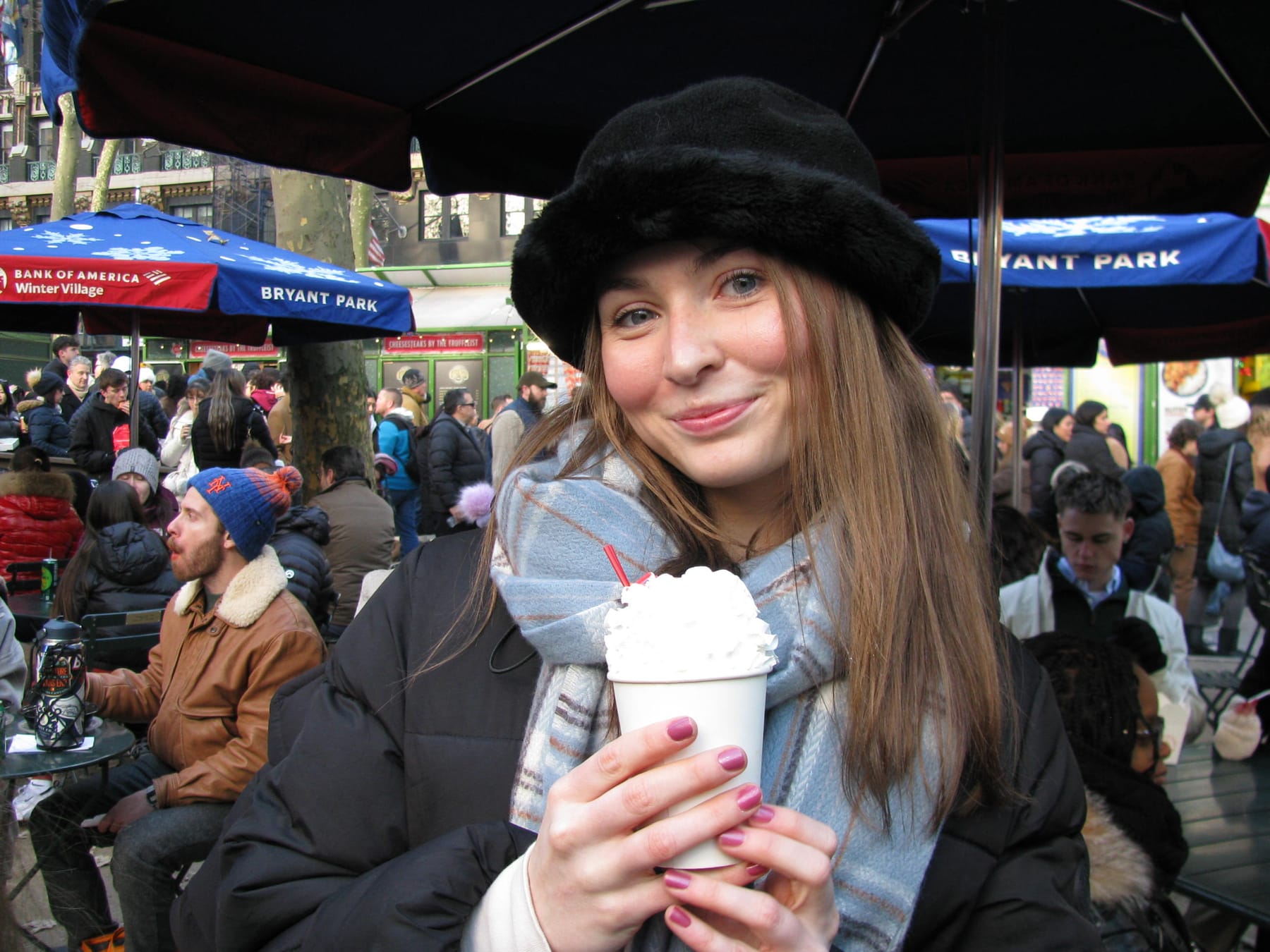 Sarah holding a hot cocoa topped with whipped cream at Bryant Park